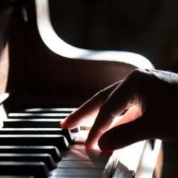 Une main droite posée sur des touches de piano.