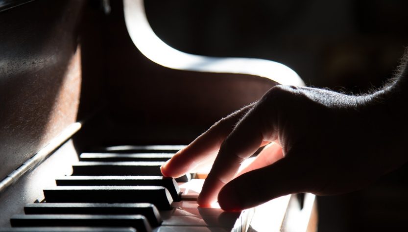 Une main droite posée sur des touches de piano.