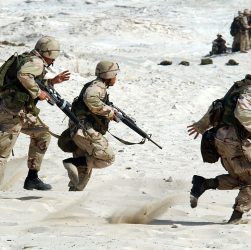 Une troupe de soldats armés qui courent dans le désert.