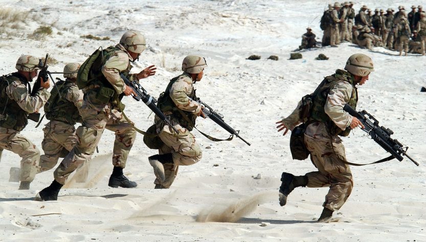 Une troupe de soldats armés qui courent dans le désert.